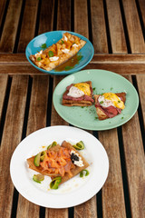 Different kinds of thin pancakes or blini with pineapple and caramel sauce, smoked salmon and caviar, poached egg and bacon