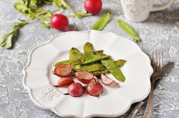 Fried young peas and radish pods. In the style of Provence. light background. Soft focus