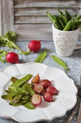 Fried young peas and radish pods. In the style of Provence. light background. Soft focus