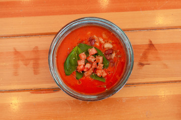Top view of seasonal vegetarian gazpacho with herbs and tomatoes on wooden table