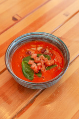 Top view of seasonal vegetarian gazpacho with herbs and tomatoes on wooden table
