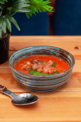 Summer seasonal gazpacho with herbs, tomatoes and basil  on a tropical background and wooden bali table