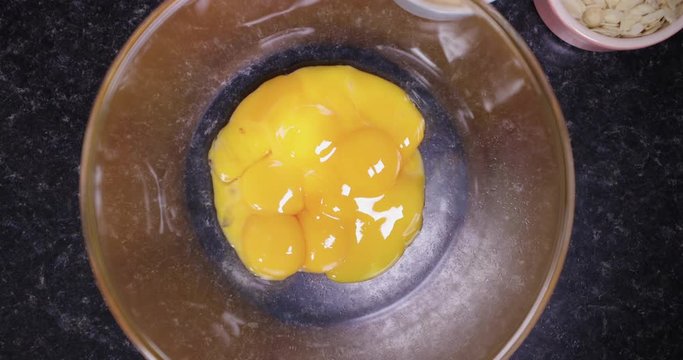 SLOW MOTION Shot of egg yolks being poured into a glass bowl to make a tasty dessert IN REVERSE - 4K shot at 30pfs