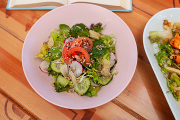 Vegetarian lunch: summer veggie salad with ripe tomatoes, cucumbers, greens and radish