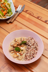Vegetarian meal with boiled wild rice and champignons in a coconut milk gravy in a fancy pink bowl