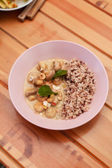 Vegetarian meal with boiled wild rice and champignons in a coconut milk gravy in a fancy pink bowl