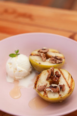 Sweet BBQ dessert: grilled apples with a nice scoop of vanilla ice cream on a light wooden table