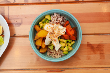 Vegetarian poke bowl with avocado, tomatoes, quinoa, rice, potato and grilled pumpkin