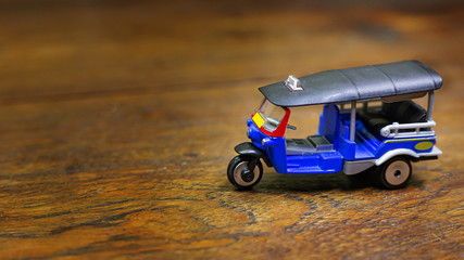 Fototapeta na wymiar tuk tuk taxi toy on wood table close up image.
