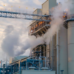 Clear Square Blue sky with puffy clouds behind the tower and buildings of a Power Plant