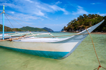 Traditional filipino banca boat in clear waters on a beach of Vigan island, also called snake island in El nido region of Palawan in the Philippines.