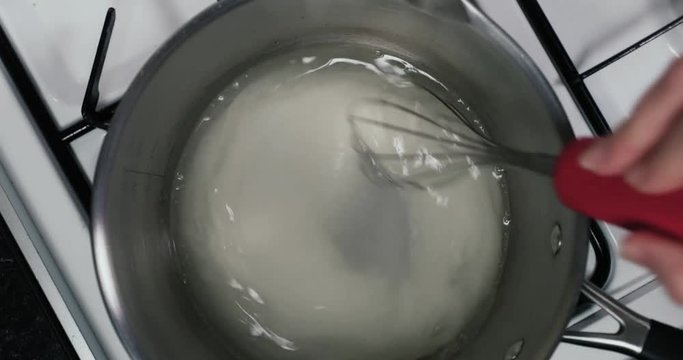 Shot of sugar and water being mixed in a pan to make syrup for a tasty desert IN REVERSE&mdash; Sugar, Water - 4K shot at 60pfs