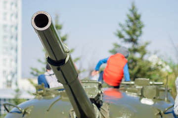 In the city Park children visiting and playing on the tower of a military tank