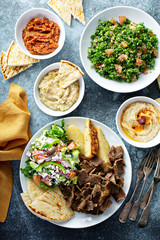 Mediterranean food on the table, gyro platter, pita and dips and tabbouleh