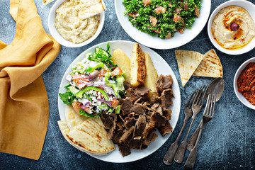 Mediterranean food on the table, gyro platter, pita and dips and tabbouleh