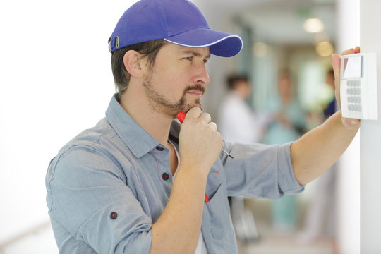 Hvac Technician Installing A Digital Thermostat