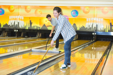 male and female workers cleaning bowling alleys