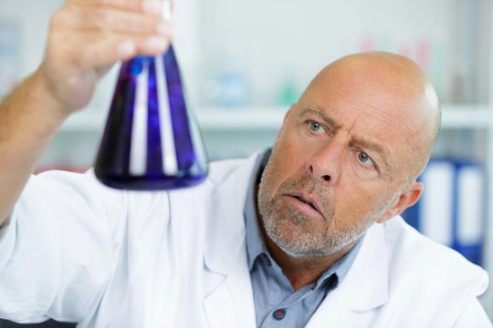 senior scientist holding flask in chemical lab