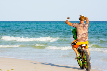 Obraz na płótnie Canvas Man Riding a Bycicle on White Sand on Blur Ocean Water Background. Destin Beach, Florida