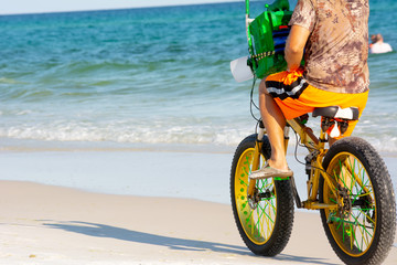 Man Riding a Bycicle on White Sand on Blur Ocean Water Background. Destin Beach, Florida
