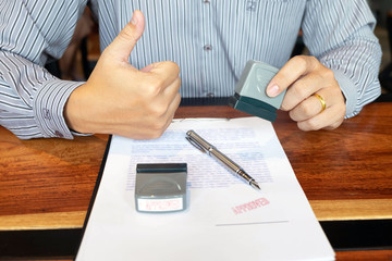 Close-up pictures of the hands of businessmen signing and stamping in approved contract forms