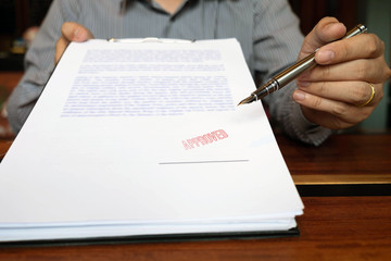 Close-up pictures of the hands of businessmen signing and stamping in approved contract forms