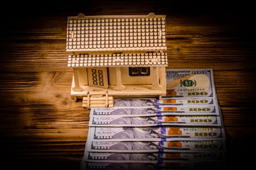 Plywood model of the house and one hundred dollar banknotes. Loan, real estate concept