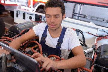 Fototapeta na wymiar young male mechanic using tablet while working on industrial vehicle