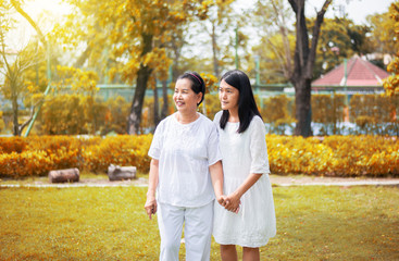 Portrait of a senior asian woman with young women walking at park together in the evening,Happy and smiling