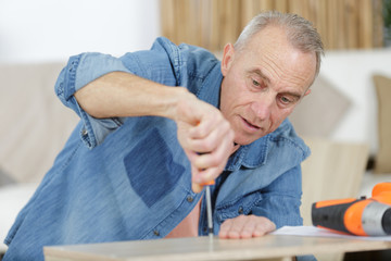 mature man screwing screws into furniture fittings