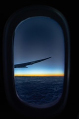 Naklejka na ściany i meble Scene of Airplane wing over the cloud and fantastic sky at sunrise time when flying above the land, taking photo via the windows, Nature and travel concept