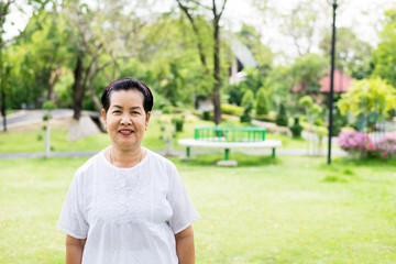 Portrait of a elderly asian woman standing and looking camera at park,Happy and smiling