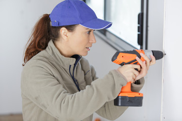 concentrated woman drilling a wall