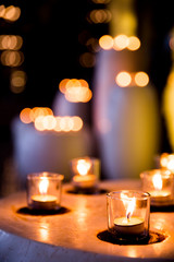 Flame of many candles burning on blurred lights background.