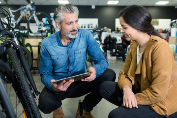 bicycle store vendor holding tablet conversing to client