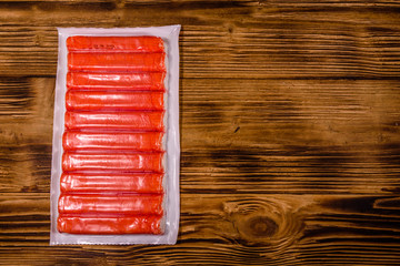 Vacuum pack of crab sticks on a wooden table. Top view