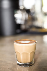 Glass of tasty latte with love art on concrete textured background.