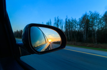 Beautiful sunset in the car mirror at high speed