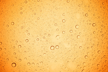 Rain droplets on yellow glass background, Water drops on yellow glass.
