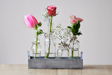 silent still life creation pink tulip and roses in four glass vase  in wooden frame on a beech table