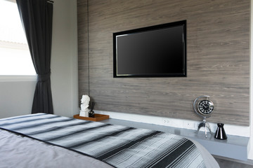 Side view of a white bedroom with a TV set on a dark wooden wall