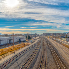Square Railroad tracks and roads with mountain and vibrant cloudy blue sky background