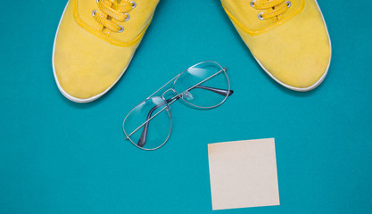 yellow sneakers, glasses  and sticker on a green background