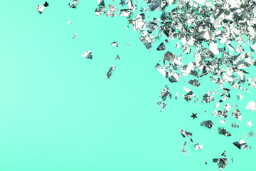 Silver foil confetti on green background.