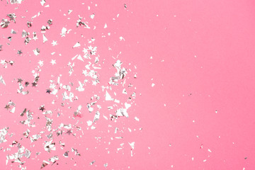 Silver foil confetti on neon pink background.