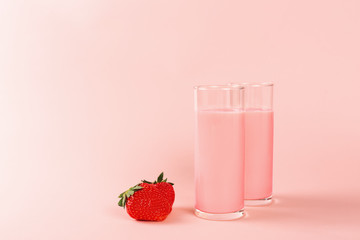 Two glasses with strawberry milk on pink background