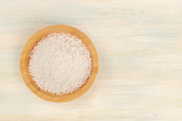 A bowl of sea salt, shot from the top on a white wooden background with copy space