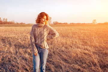 Outdoor fashion photo of young beautiful woman in  brown knitting sweater and jeans in autumn field...