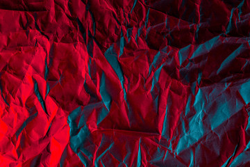 Texture of crumpled black paper. Close up black background of crumpled cardboard under color red and blue studio light
