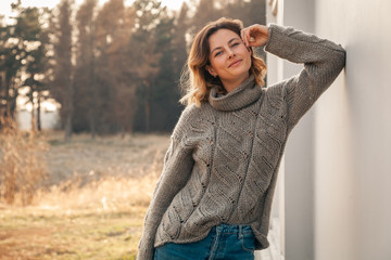 Outdoor fashion photo of young beautiful woman in  brown knitting sweater and jeans in autumn field  landscape. Fashion lookbook.